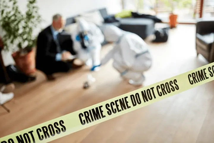 crime scene tape with people cleaning in the background